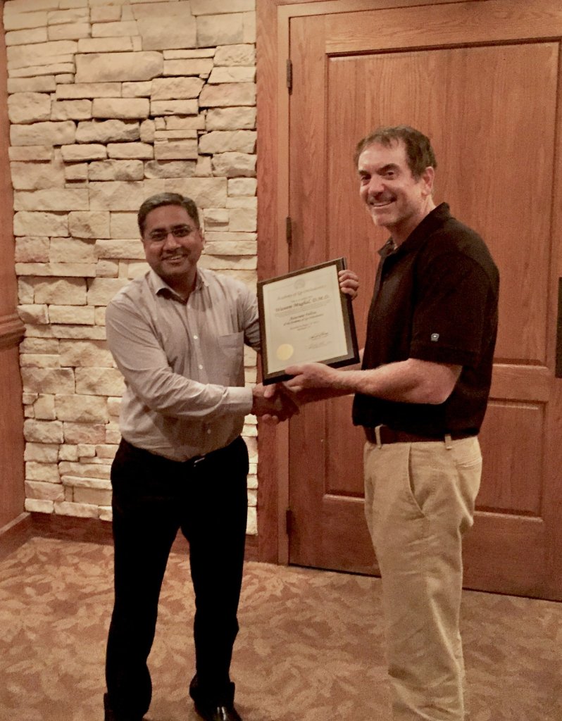 Dr. Mughal holding a certificate